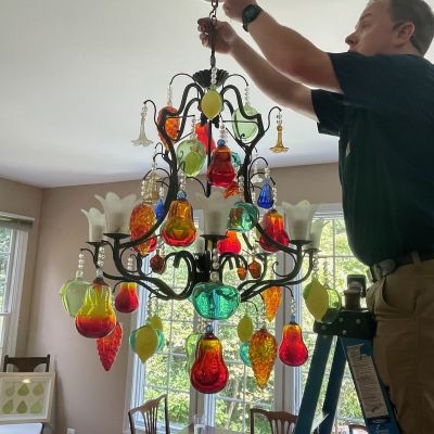Chandelier Repair Man On Ladder Working On Light Fixture