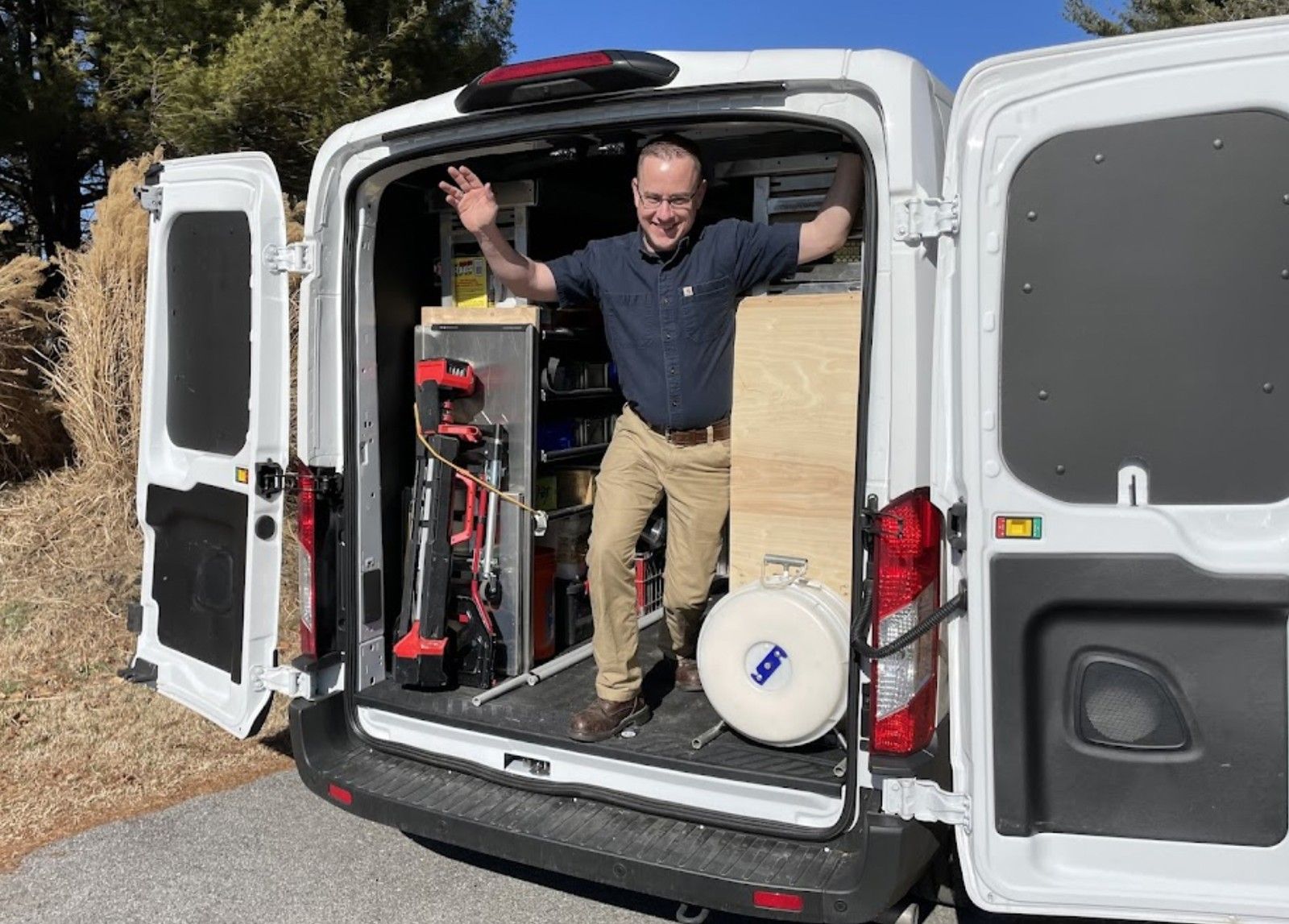 Man Standing Inside Work Van With Tools And Equipment