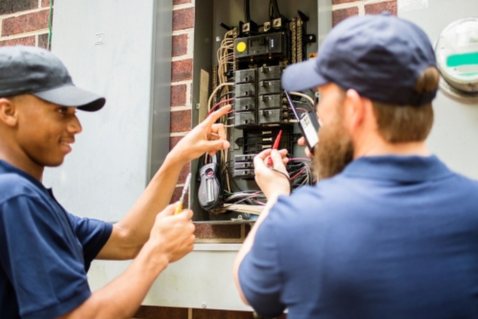 Electricians Working On Circuit Breaker Panel With Tools