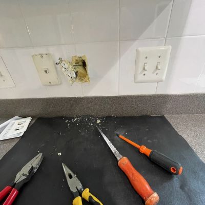 Damaged Wall Outlet Repair Tools And Debris On Countertop