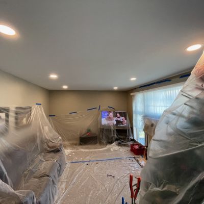 Living Room Being Painted With Plastic Sheets And Lighting