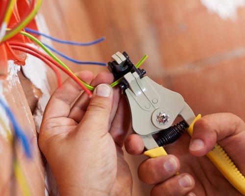 Electrician Using Wire Strippers On Cables In Wall Hanover Md