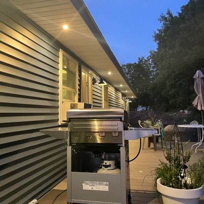 Grill On Porch At Dusk With Lighting And Furniture Outside