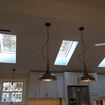 Skylights And Pendant Lights In Modern Kitchen With White Cabinets