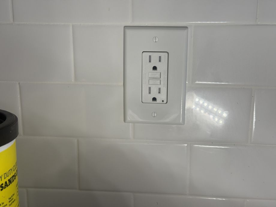 Wall Outlet On White Tile Background With Cleaning Supply