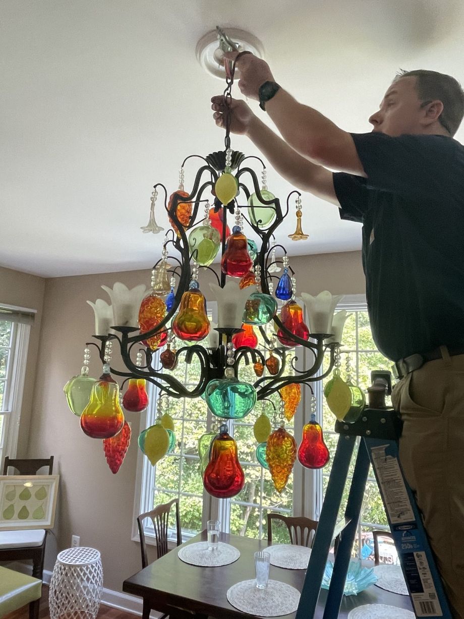 Repairing Colorful Chandelier In Dining Room With Ladder