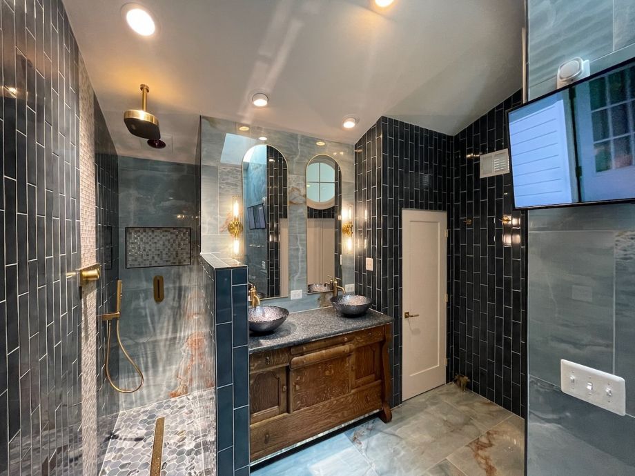 Modern Bathroom With Dark Tiles And Wooden Vanity And Mirrors