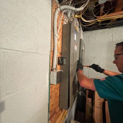 Electrician Working On Electric Panel In Basement